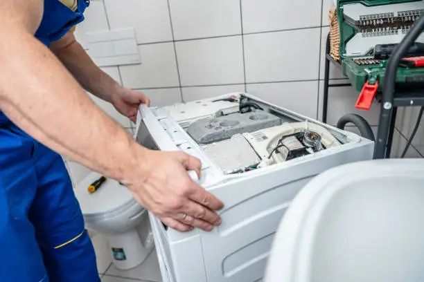 Illustration of water on the floor beside a washing machine with a leaking hose